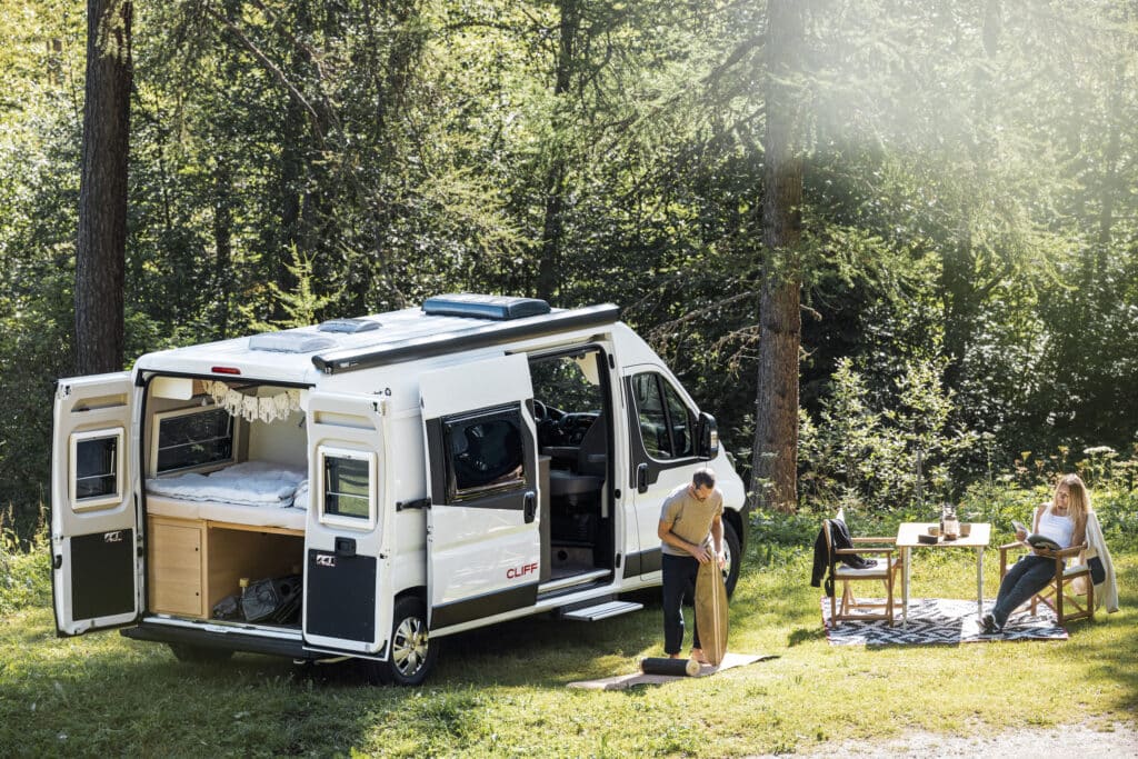 Ein Sunlight Campervan steht am Waldrand auf einem Stellplatz.